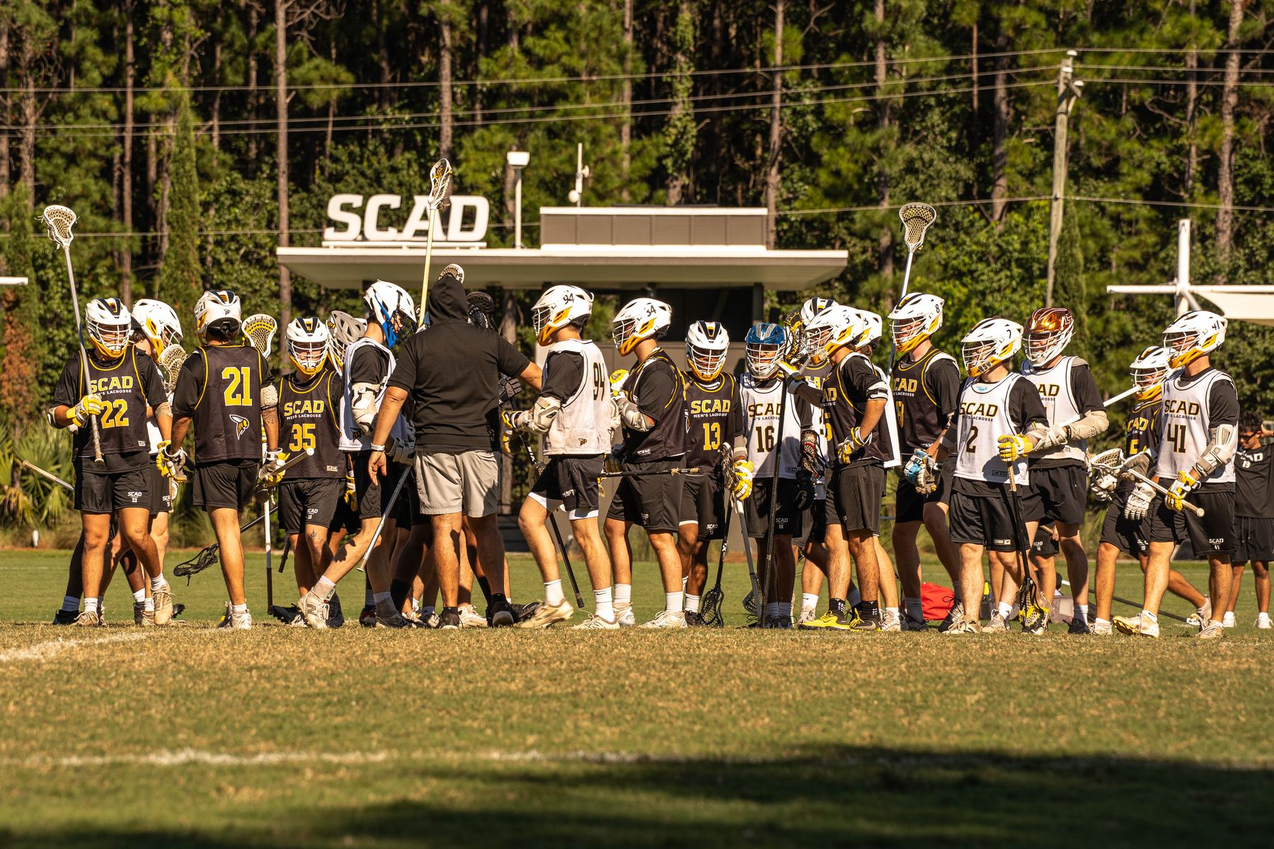 SCAD men&rsquo;s lacrosse players gathered on the field during an alumni event.
